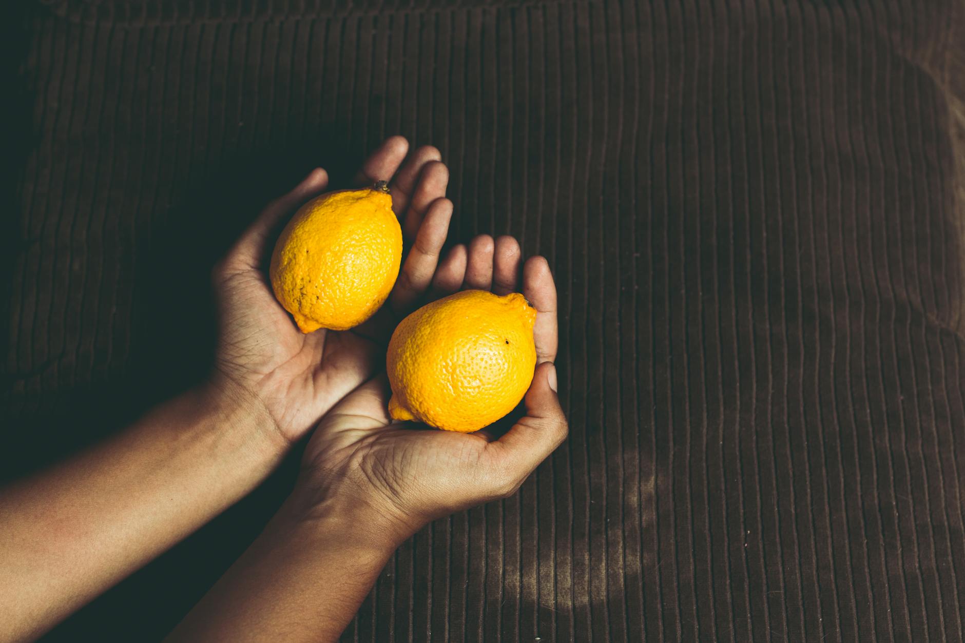 Close-up of a hand holding an orange vibrator against a purple backdrop