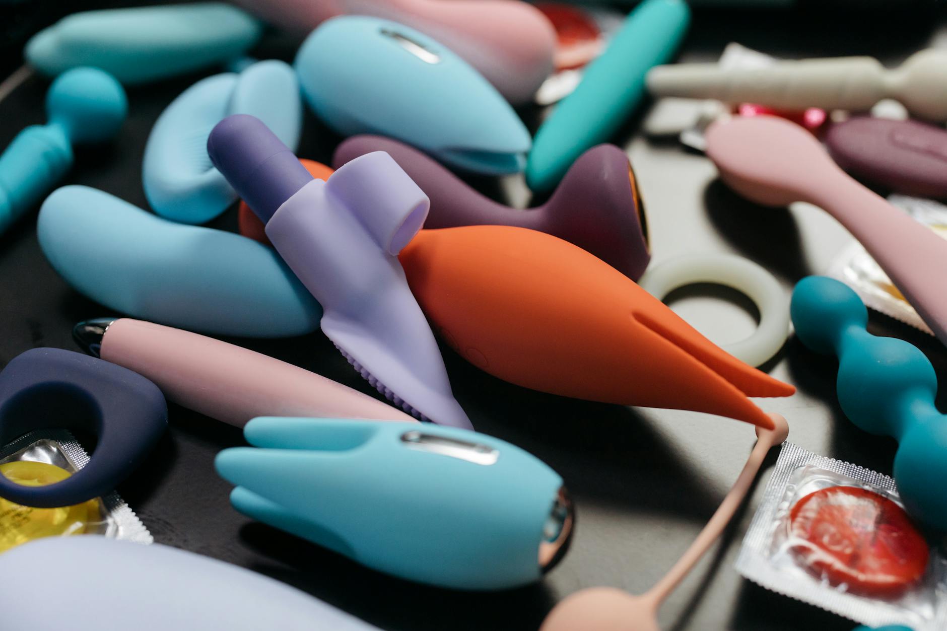 A sleek teal clitoral vibrator on soft white silk fabric