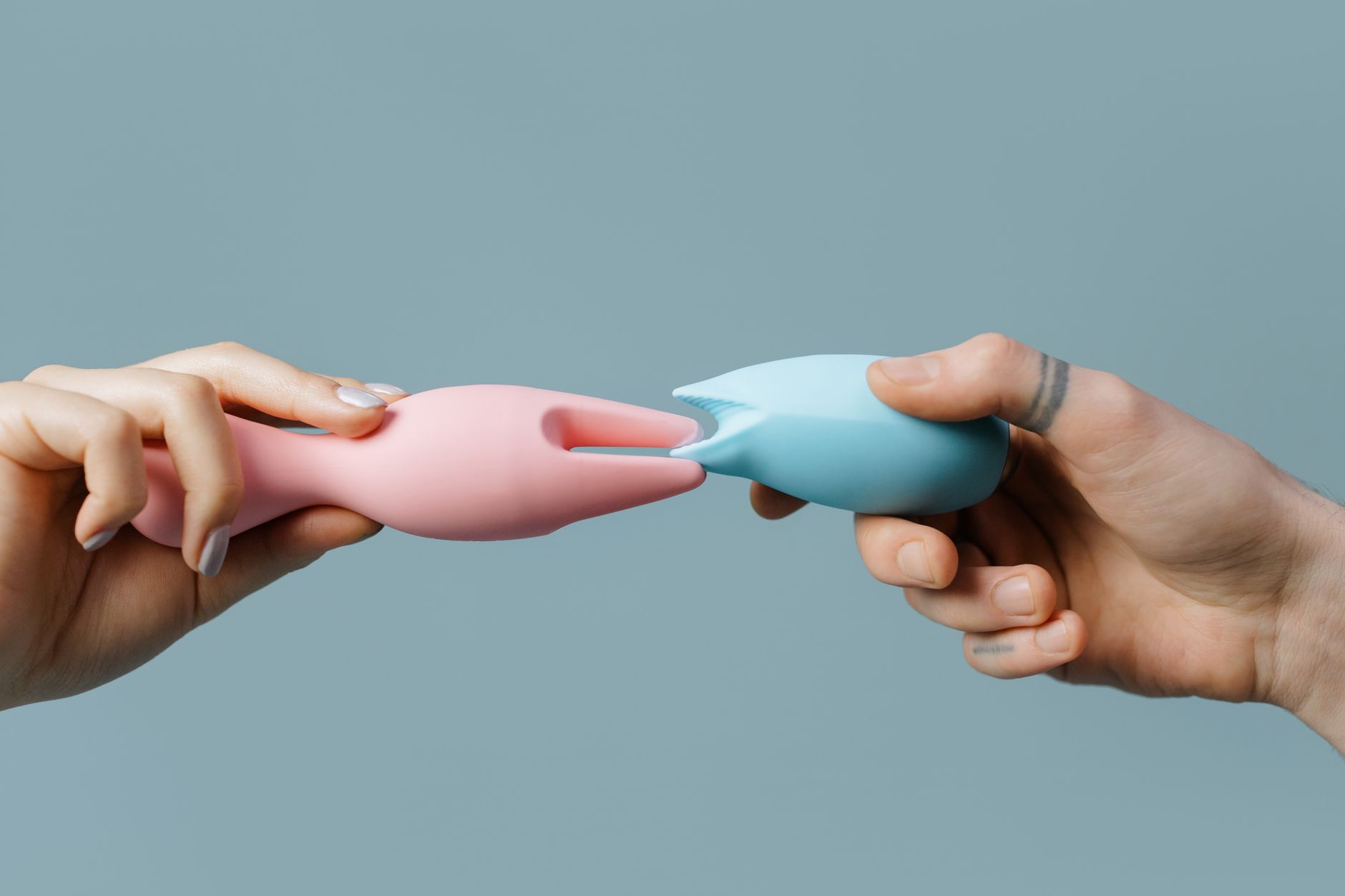Hands holding pastel-colored silicone toys against a soft background
