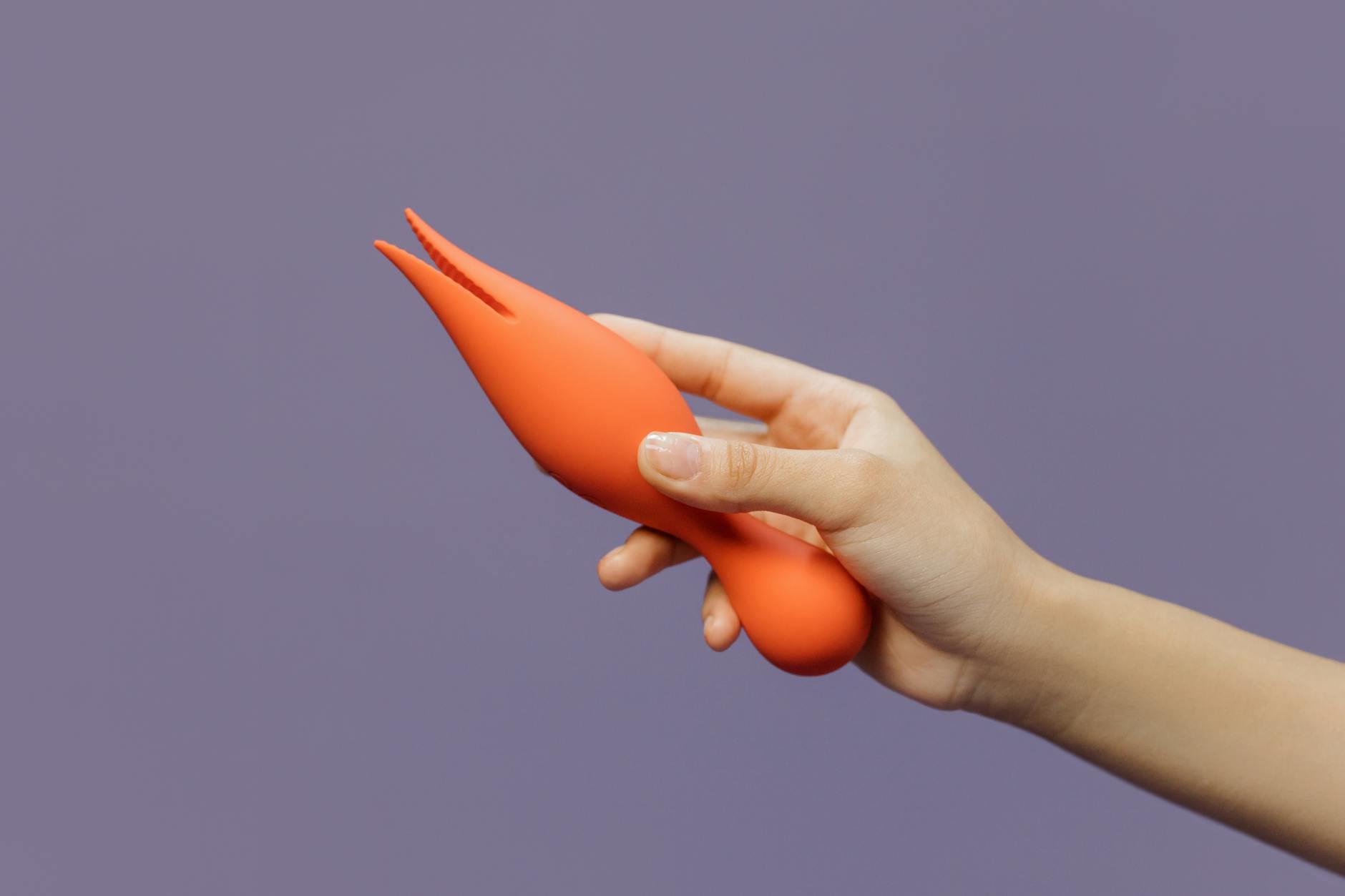 A hand holding a lemon-colored vibrator against a minimalistic purple backdrop, showcasing modern sensuality and pleasure.